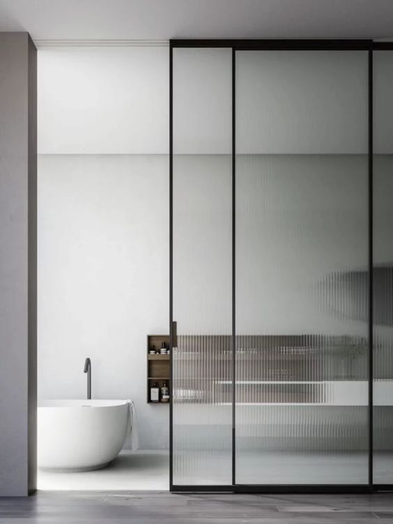 a contemporary bathroom with a reeded glass sliding door, an oval tub, a wooden cbainet is a refined and clean space