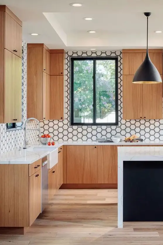 a cool modern kitchen with light-stained flat panel cabinets, a white hex tile backsplash and a black kitchen island