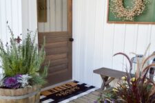 a cozy rustic entrance with a stained Dutch door, layered rugs, a bench, potted plants and blooms, a wreath in a frame