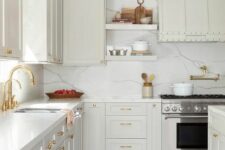 a creamy farmhouse kitchen with white quartz countertops and a backsplash, gold and brass fixtures is amazing