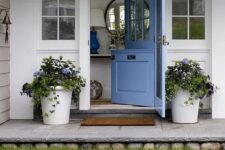a cute blue Dutch door and matching potted flowers on both sides that echo with the door to make the entrance welcoming