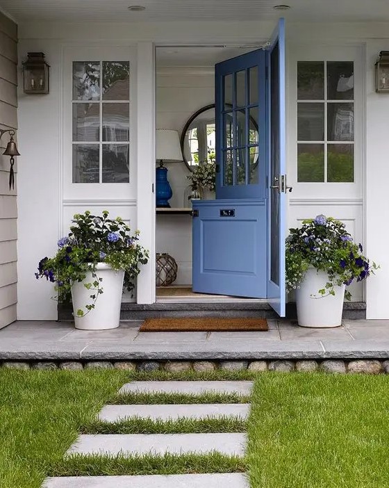 a cute blue Dutch door and matching potted flowers on both sides that echo with the door to make the entrance welcoming