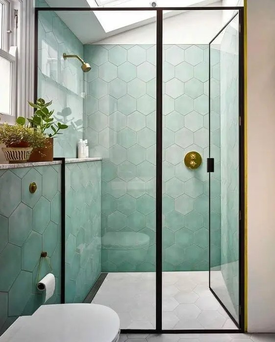 a delicate bathroom with green hexagon tiles, a skylight, black frames and potted plants, white appliances
