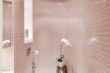 a delicate blush bathroom all clad with tiles, with a window, white appliances and a potted orchid for a touch of luxury