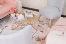 a delicate living room with a pink sofa, pale blue chairs, a pastel floral print rug, a hexagon table with decor