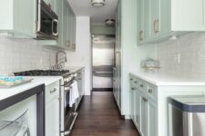 a delicate mint blue kitchen with shaker cabinets, a white skinny tile backsplash, a table and tall acrylic stools is chic
