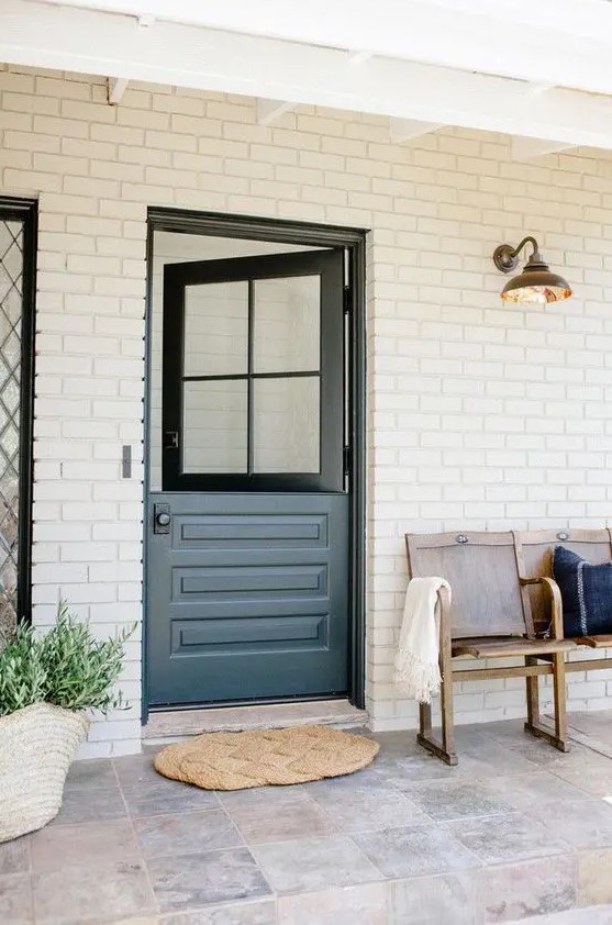 a farmhouse entrance with a bench, a graphite grey Dutch door and a jute rug plus greenery in a basket is very welcoming