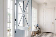 a farmhouse entryway with a checked floor, a printed rug, a light blue Dutch door, French windows and a bench