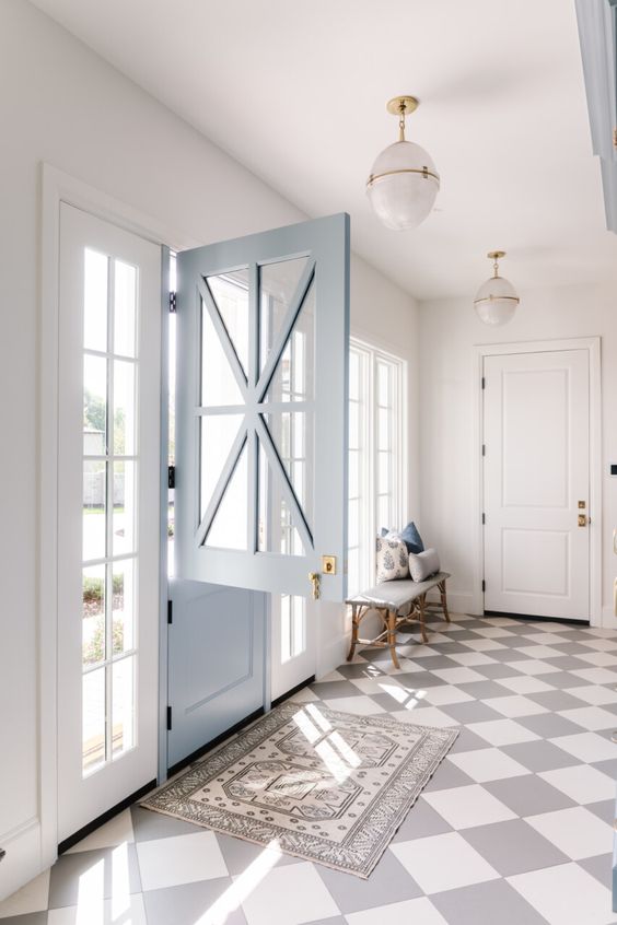 a farmhouse entryway with a checked floor, a printed rug, a light blue Dutch door, French windows and a bench