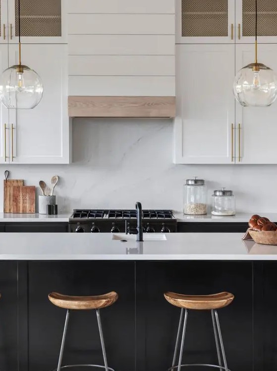 a farmhouse kitchen with white shaker cabinets, a black kitchen island, a white quartz backsplash and countertops, pendant lamps
