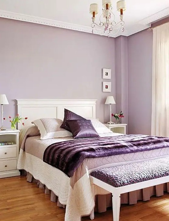 a feminine bedroom with lilac walls, purple accessories and an upholstered bench is a chic and refined idea