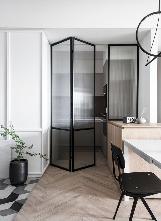 a folding fluted glass door lets enterign the kitchen, lets some light inside and connects the spaces more