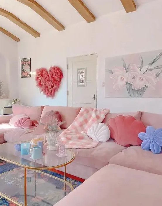 a fun girlish living room with a blush corner sofa, a glass tiered table, a pink grass heart and lots of pastel pillows