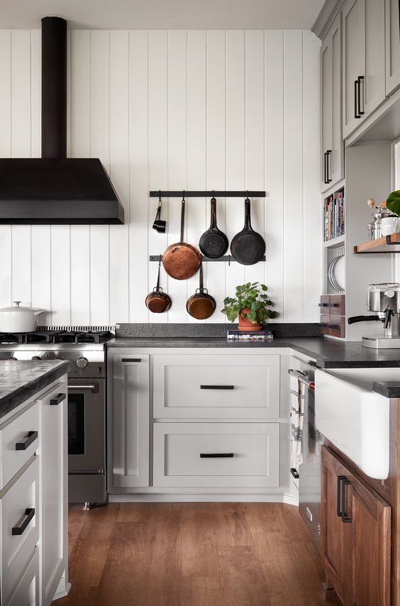 a grey and white kitchen with black granite countertops, a black hood and black handles is a very chic space