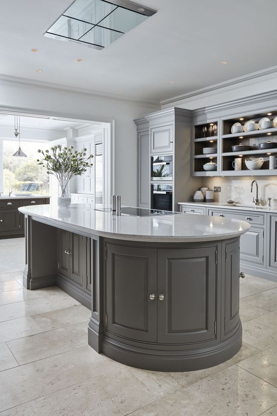 a grey kitchen with a vintage feel, with beautiful cabinets, an open cabinet, a curved kitchen island and lots of light