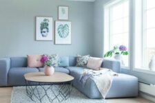 a grey living room with a dusty blue low sofa, printed and pastel pillows, a coffee table and a grey rug is a lovely space