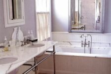 a lilac bathroom with a bathtub enclosed in marble, a free-standing double vanity, a shabby chic mirror cabinet and a large mirror