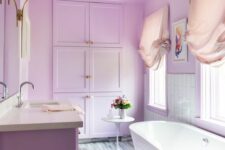 a lilac bathroom with a lilac vanity and built-in cabinets, an oval tub, blush curtains and a floral chandelier