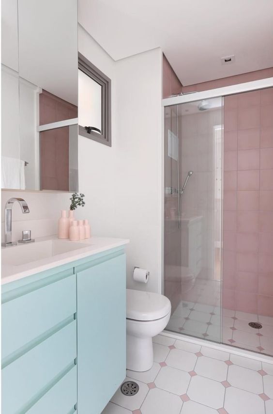 a lovely neutral bathroom with dusty pink tiles in the shower and a mint floating vanity, some touches of pink here and there