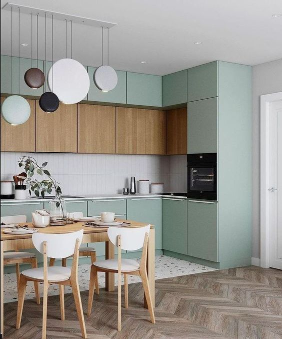 a lovely sage green kitchen with stained cabinets, a skinny tile backsplash, a very eye-catchy pendant lamp arrangement