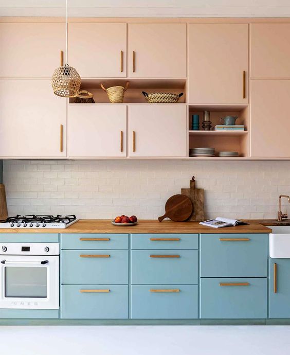 a mid-century modern two-tone kitchen with pink and blue cabinets, a white subway tile backsplash and woven pendant lamps
