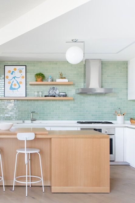 a mid century modern white kitchen with a mint green tile backsplash, a stained kitchen island and open shelves