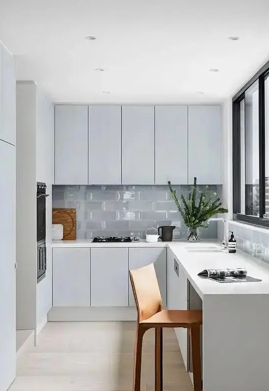 a minimal Nordic L-shaped kitchen with glass tiles and a window with a view is a lovely idea