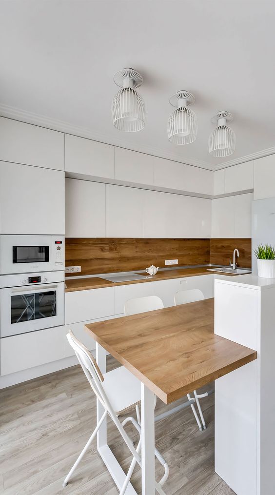 a minimalist kitchen with sleek white cabinets, a wooden backsplash and countertops, a kitchen island that doubles as a table