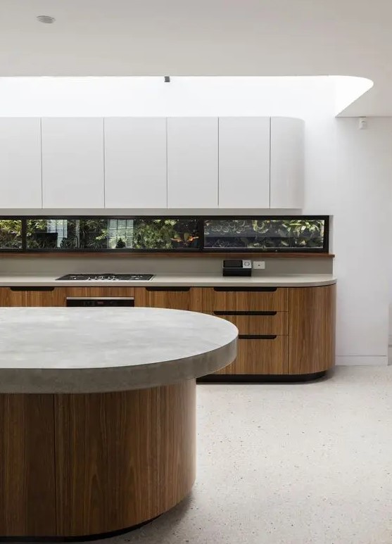 a minimalist kitchen with stained and sleek white curved cabinets, a window backsplash and a curved kitchen island with a stone countertop