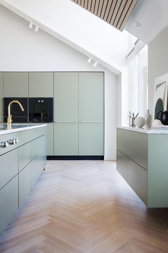 a minimalist sage green kitchen with flat panel cabinets, white stone countertops and gold fixtures is amazing