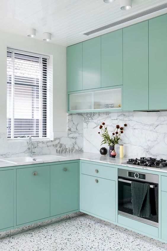 a mint blue kitchen with a white terrazzo floor, a white marble backsplash and countertops is a lovely and chic space