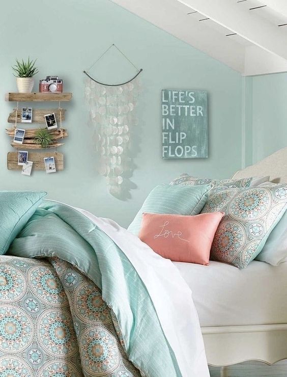 a mint green bedroom with a white bed and pastel bedding, some coastal decor on the wall is amazing
