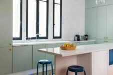 a mint green flat panel kitchen with a pink kitchen island, a black printed tile floor, black stools and pendant lamps
