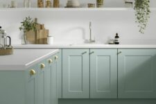 a mint green lower cabinet kitchen with white tone countertops and a large open shelf, brass and gold handles