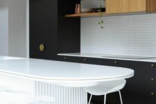 a modern black kitchen with a square tile backsplash, a fluted cabinet, a white curved and fluted kitchen island