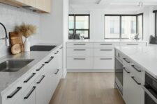 a modern Scandinavian kitchen with light-stained and white flat panel cabinets, black handles and lots of natural light