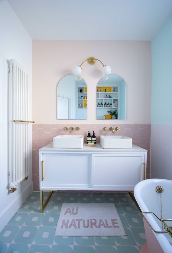 a modern bathroom in a mix of pastels - mint, blush and lilac, with pretty tiles, a modern vanity, a pink tub and a cool rug