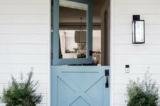 a modern beach entrance with a blue Dutch door and matching pots with succulents, a black wall lamp