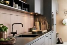 a modern dark-stained kitchen with black countertops, a peachy pink tiel backsplash, box shelving, black fixtures