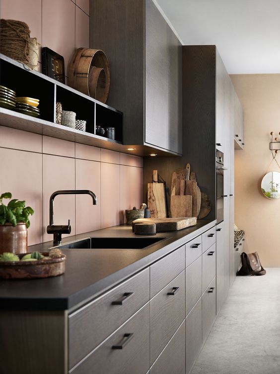 a modern dark-stained kitchen with black countertops, a peachy pink tiel backsplash, box shelving, black fixtures