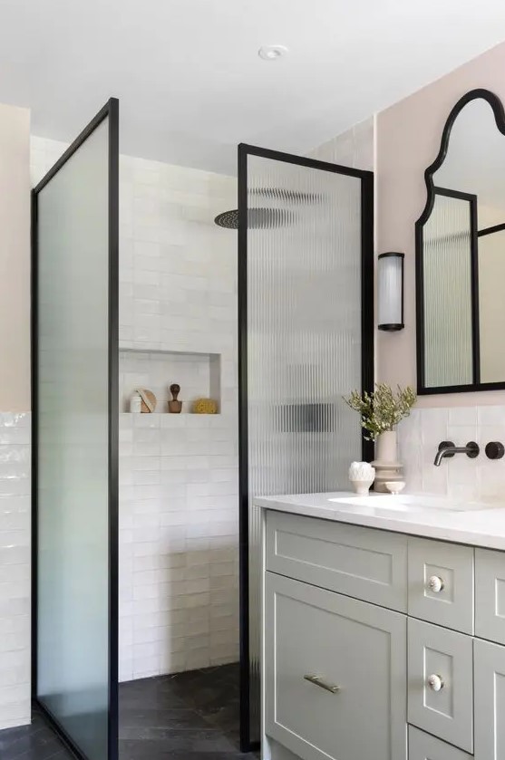 a modern farmhouse bathroom clad with white tiles, a greige vanity, fluted glass space dividers and black fixtures