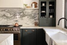 a modern farmhouse kitchen with graphite grey cabinetry, a white quartz backsplash and countertops, black fixtures and gold sconces