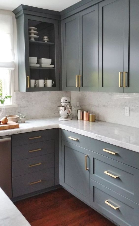 a modern farmhouse kitchen with graphite grey kitchen cabinets, a white quartz backsplash and countertpos and gold handles