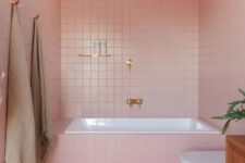 a modern glam bathroom clad with pink tiles and finished off with brass and gold fixtures for a chic look