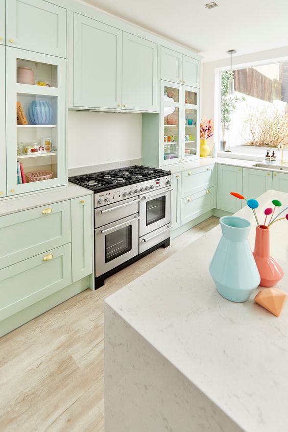 a modern mint green kitchen with shaker cabinets, white countertops and a backsplash, gold handles is a lovely and chic space