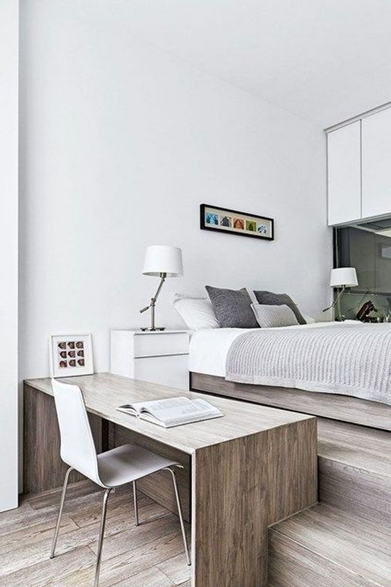 a neutral contemporary bedroom with sleek cabinets, glass, a bed with neutral bedding, a sleek desk and a white chair