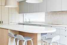 a neutral kitchen with dove grey flat panel and stained cabinets, a curved kitchen island, tall stools and pendant lamps