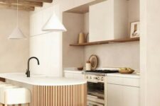 a neutral warm-colored kitchen with sleek cabinets, an open shelf, a curved and fluted kitchen island and pendant lamps