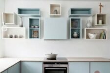 a pastel blue Scandinavian kitchen with sleek cabinets, box shelves on the wall and built-in appliances