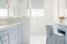 a pastel blue and white bathroom with a herringbone tile floor, a dusty blue vanity and a makeup table, a shower space and mirrors